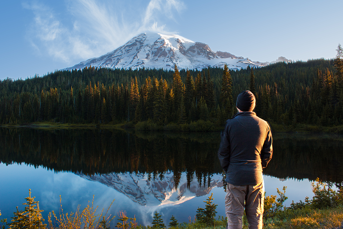 A man standing looking at the peak of Mt. Ranier in the distance